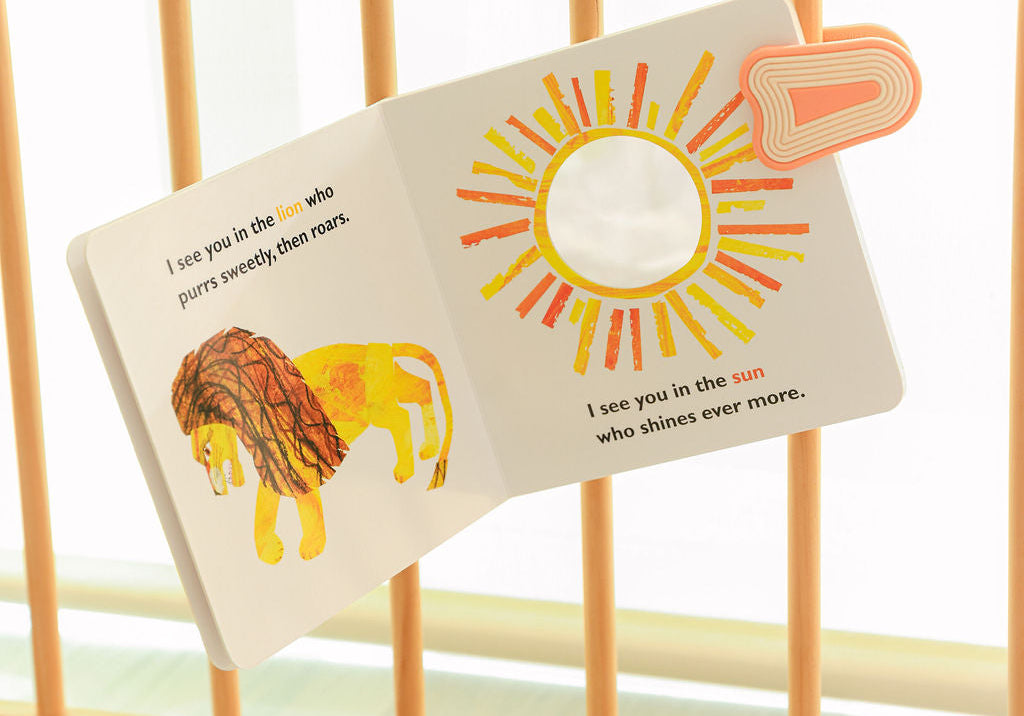 Children's board book clipped to a crib rail with a whimSi silicone stroller clip to keep books and toys within easy reach.
