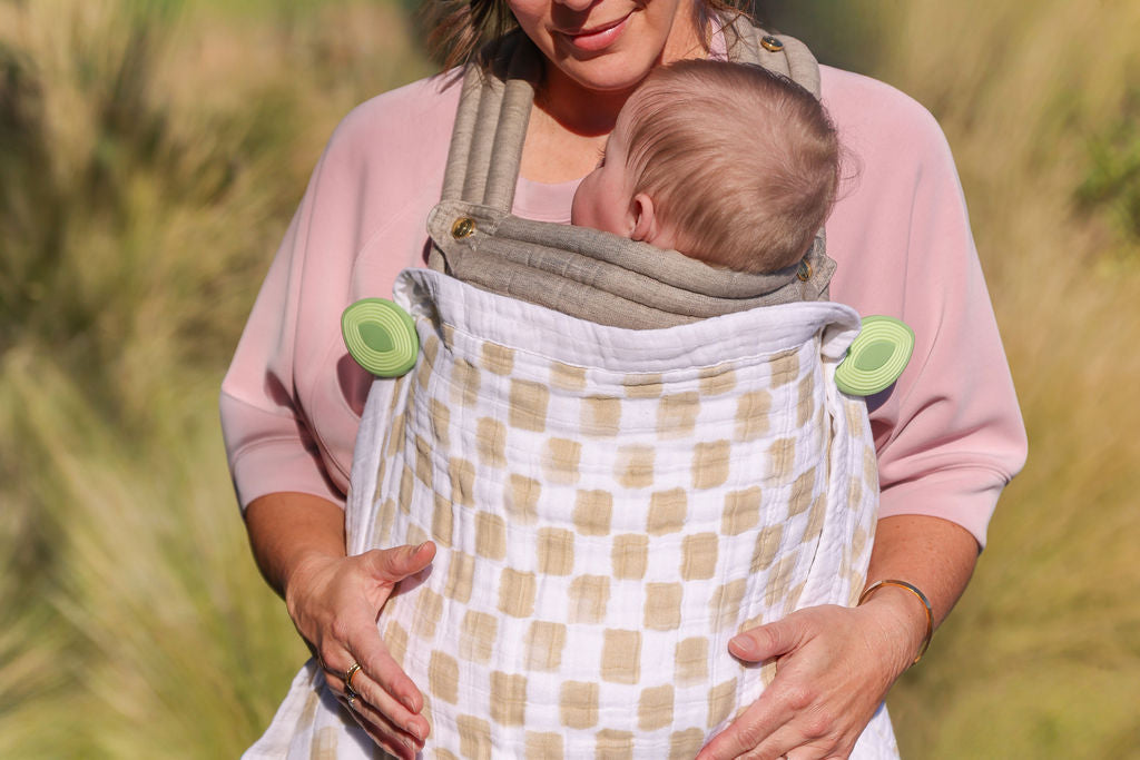 Mom babywearing with Wind whimSi silicone clip holding baby blanket in place — hands-free and secure