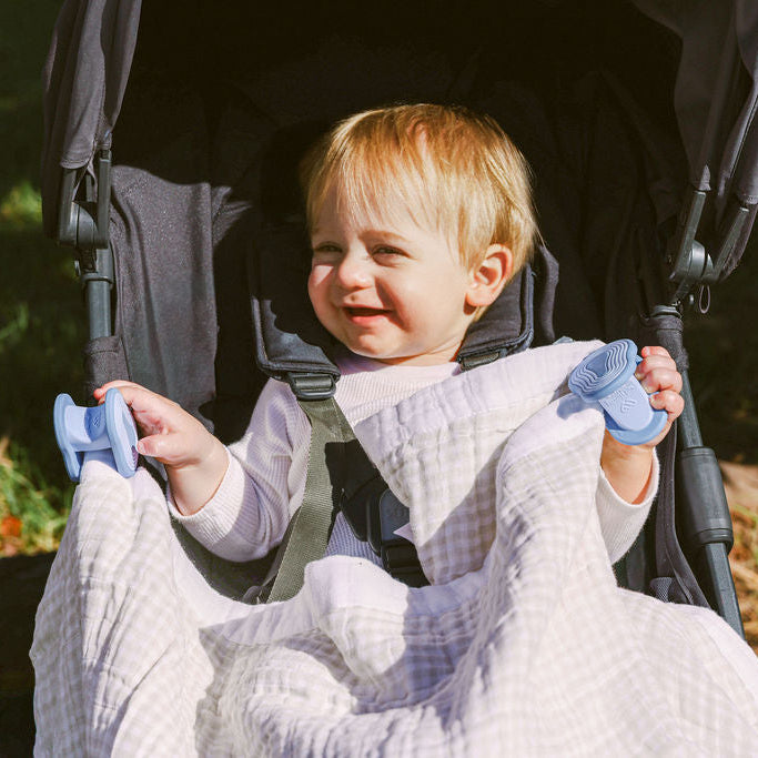 Baby in stroller with water whimSi clips holding a blanket in place to keep him warm.