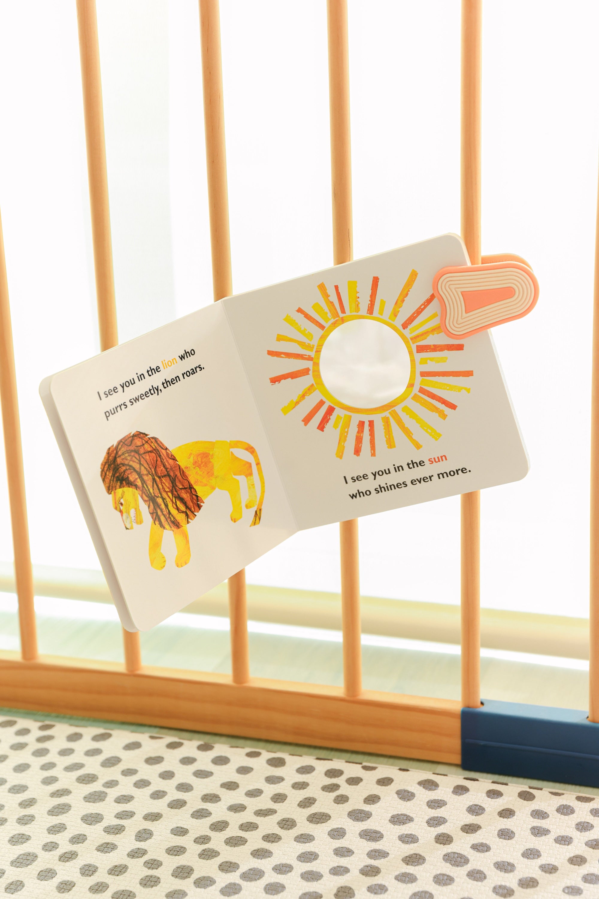 whimSi clips silicone clip close-up holding a book in play pen by a play mat. Best baby registry product 2026