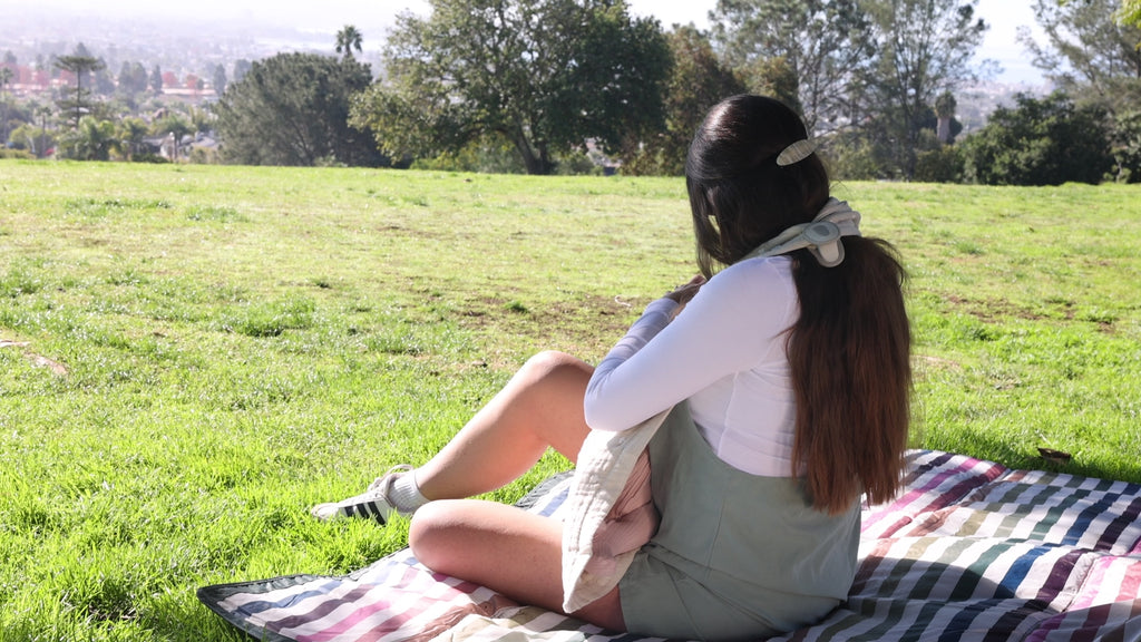 mom nursing at park using whimSi clips to hold a nursing cover conveniently in place
