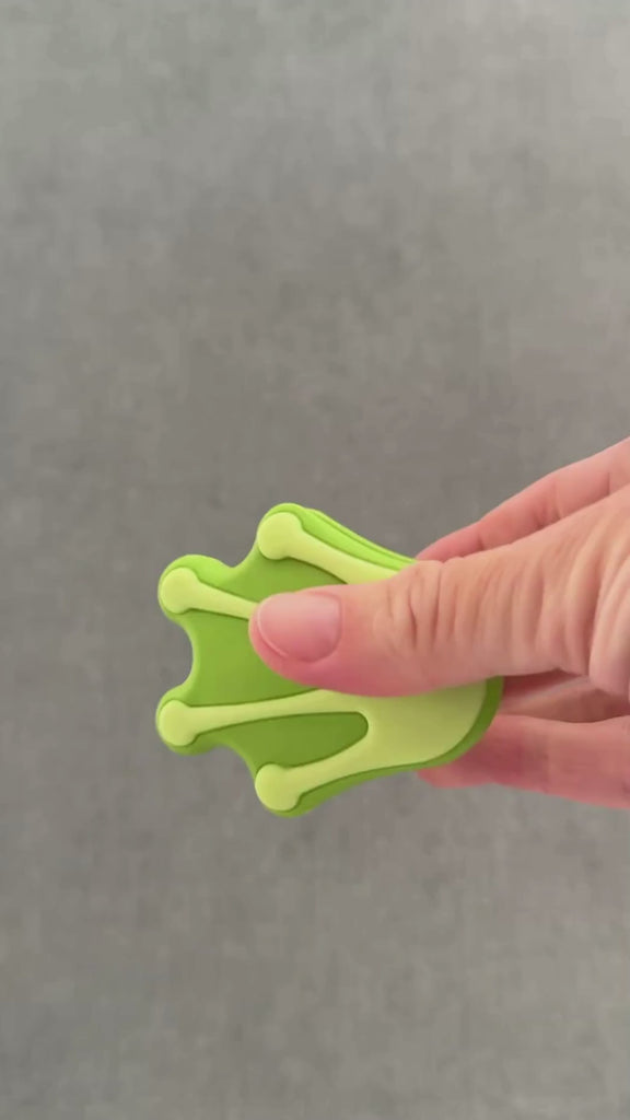 Hand squeezing froggy foot whimSi clip design.  opening and closing soft silicone clip with innovative silicone spring