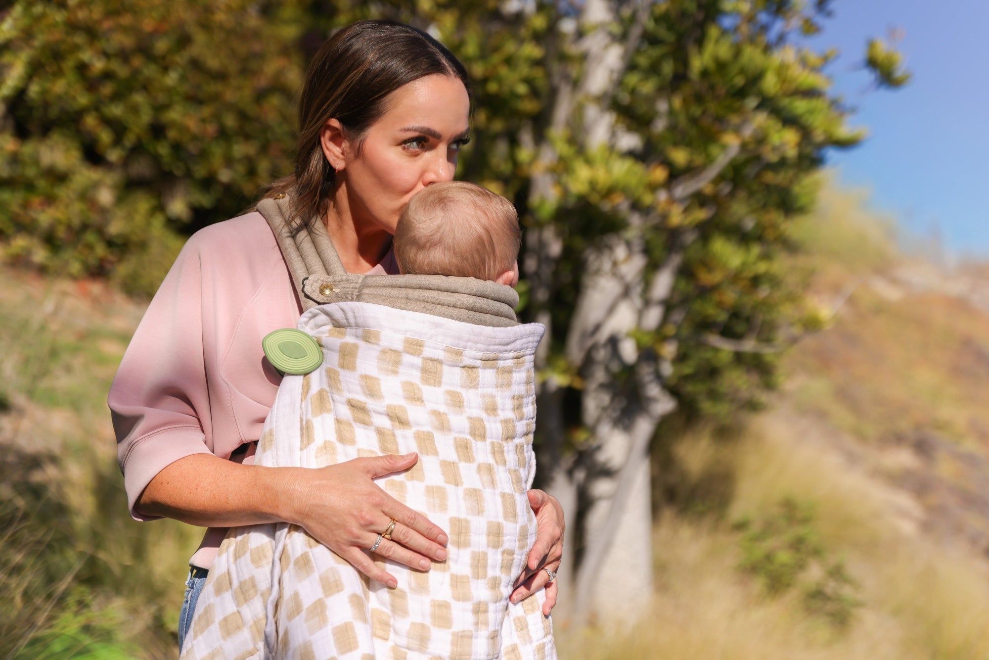Babywearing with an Artipoppe carrier outdoors, featuring safe whimSi clips securing blanket to keep baby warm.