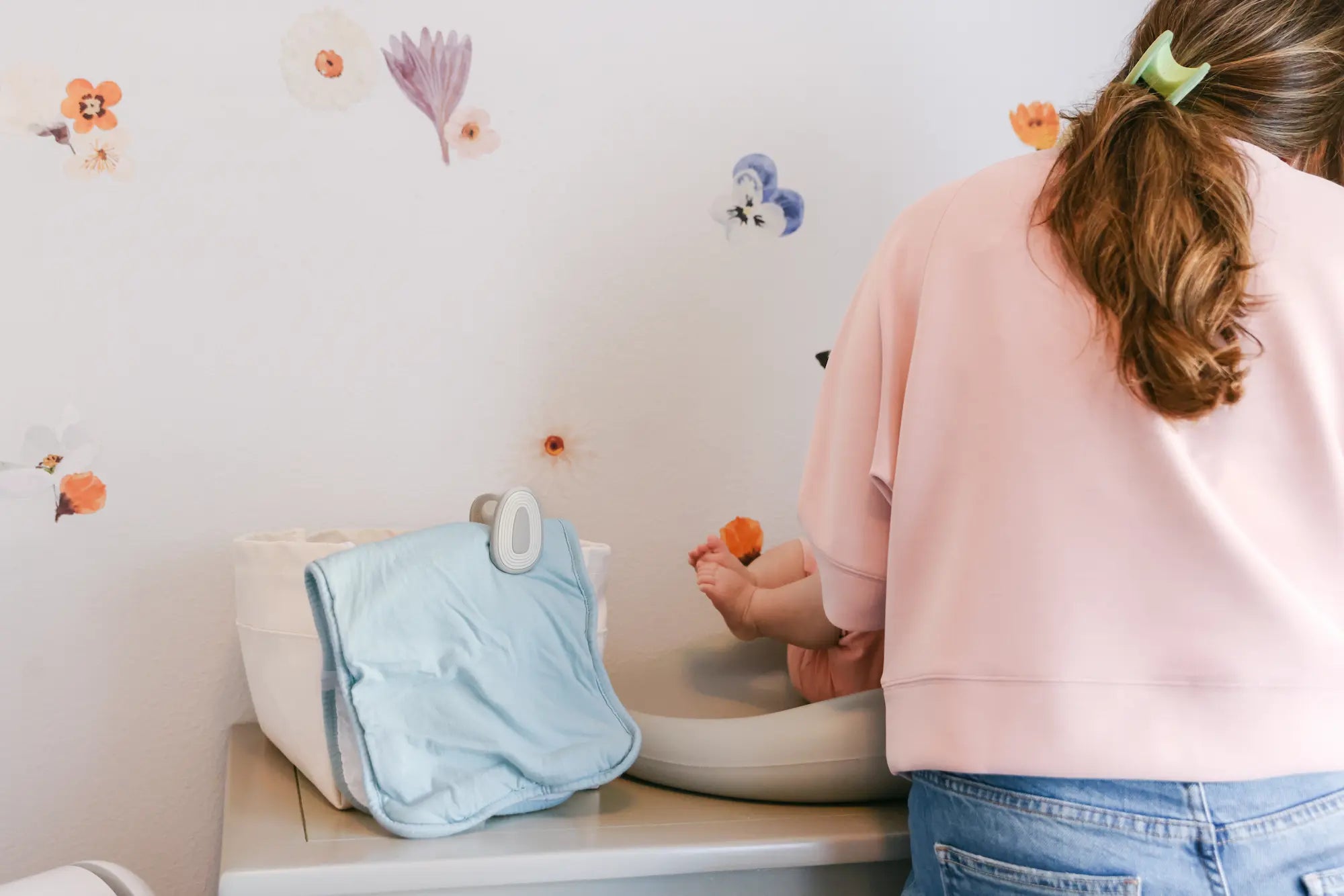 A mom in a pink sweatshirt with a blue diaper bag clipped using whimSi clips — the perfect baby shower and baby registry gift for new parents in San Diego and beyond